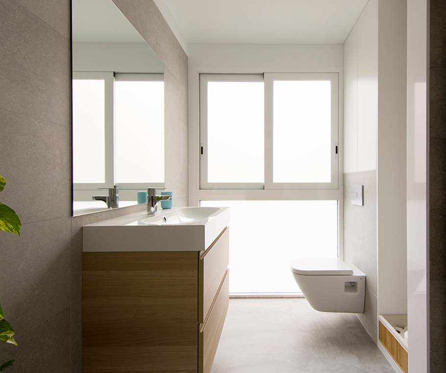 Salle de bain rénovée avec microciment au sol de couleur grise.