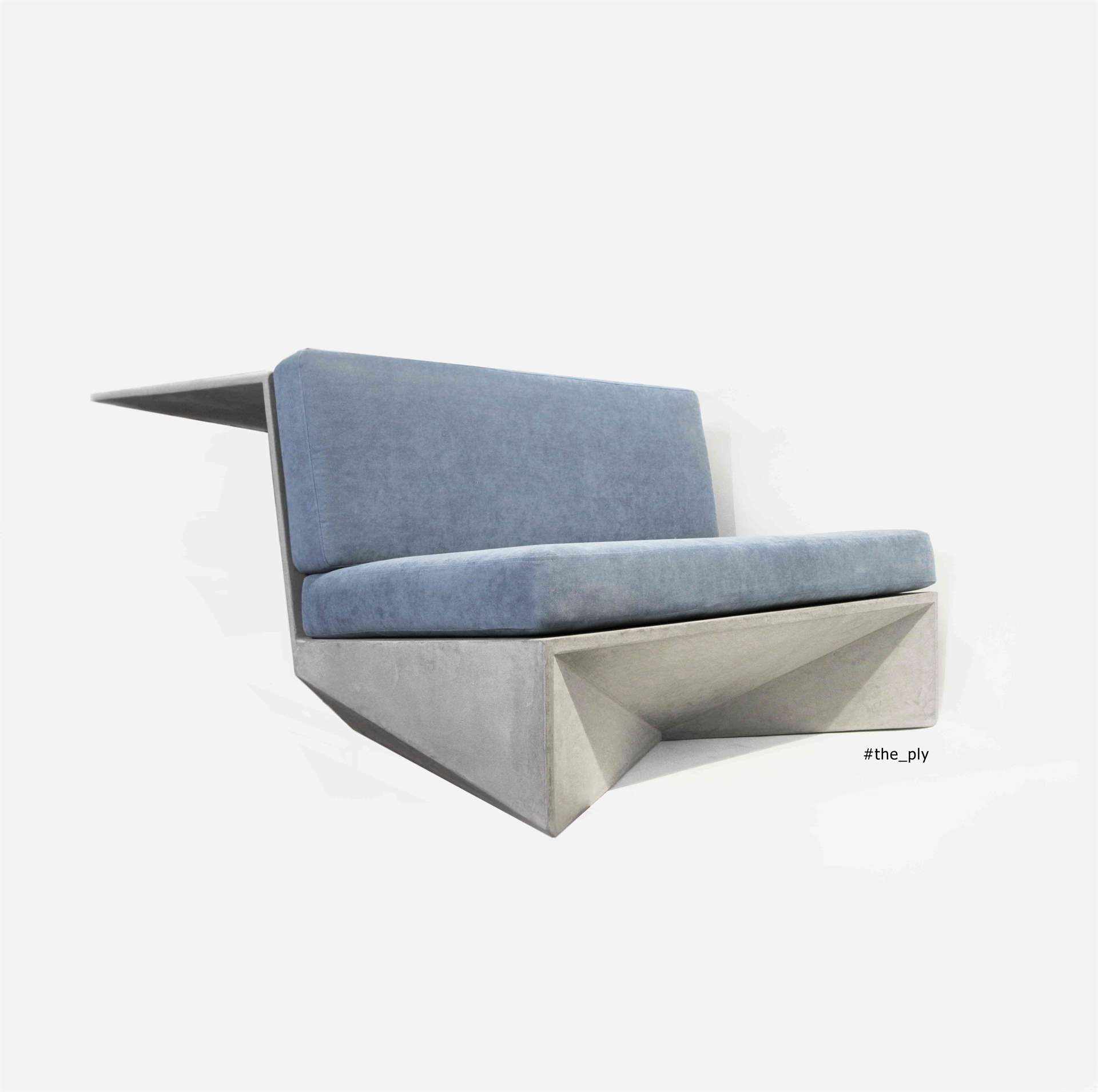Canapé en béton ciré de couleur grise avec des coussins bleus.