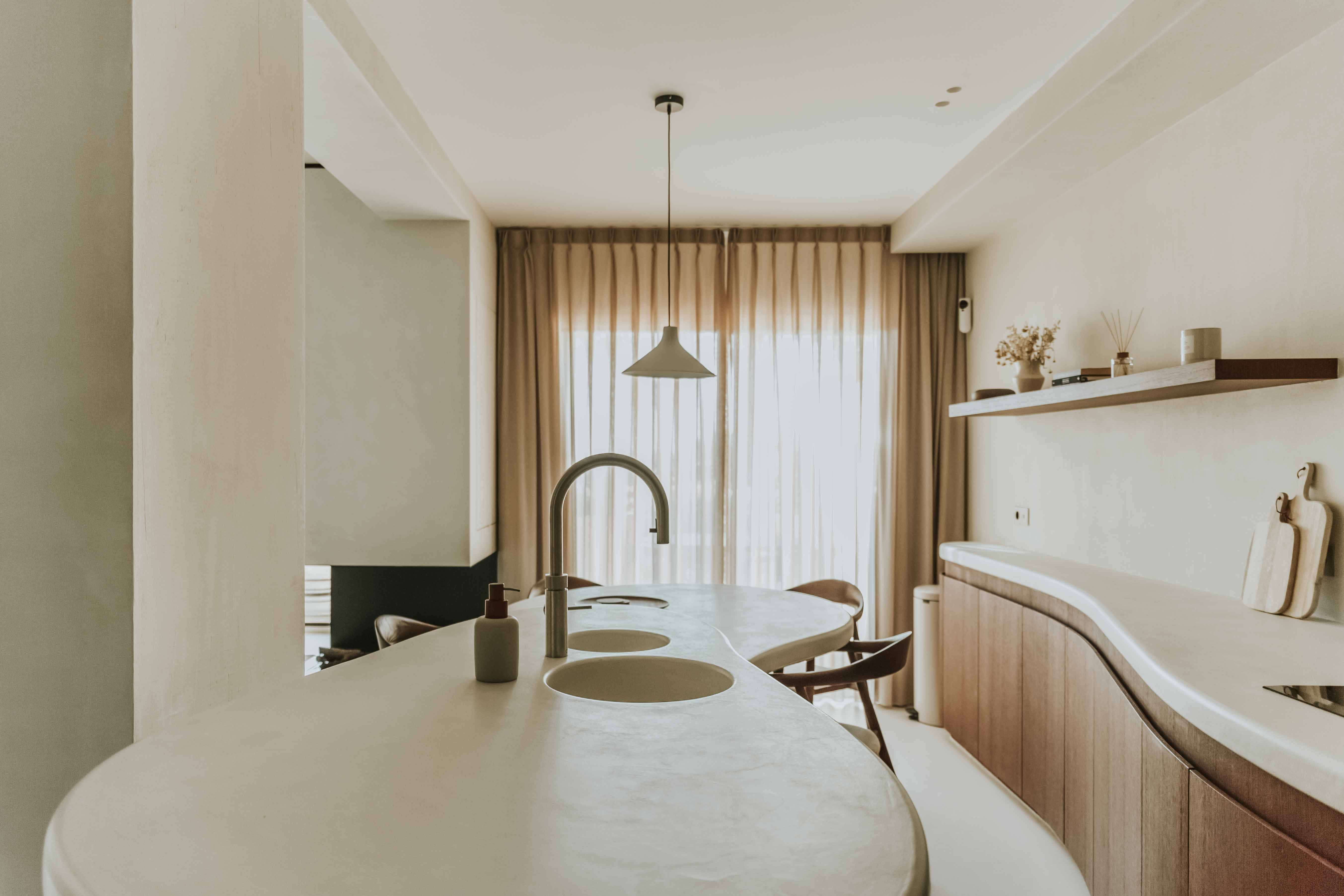 Bright kitchen with Topciment® microcement applied on the countertop and island, creating a continuous, minimalist and durable surface.