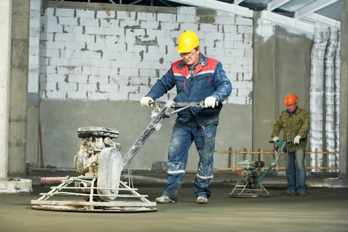 Hommes utilisant une talocheuse pour béton taloché